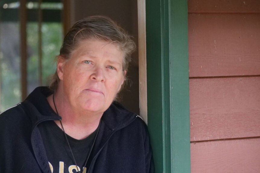 Lee Rimmer stands leaning in the door way of her home.