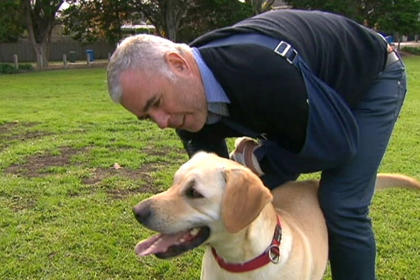 Cam McIntyre holds and pets his labrador named Mick.