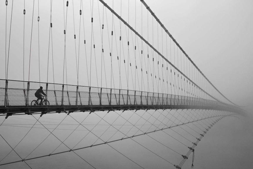 A traveller is seen riding across Ram Jhula bridge in India.