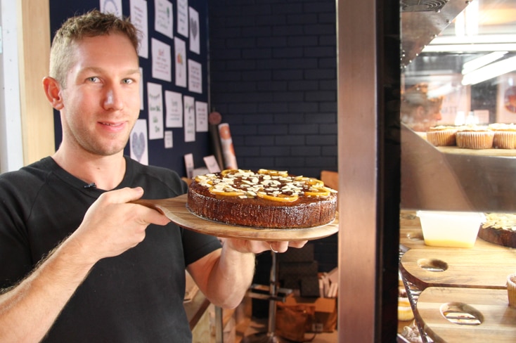 Mr Nosworthy in his bakery holding a gluten-free cake