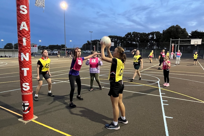 Netball players on the court shooting for goal and defending