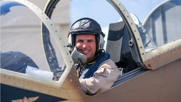 a fighter pilot sitting inside his jet looking and smiling at the camera