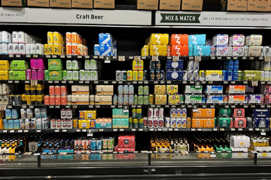 beer cans next to eachother in a fridge in different colours and brands