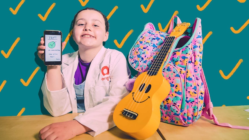 Lucia smiles while holding up a phone with her app displayed. Ukulele and bag next to her.