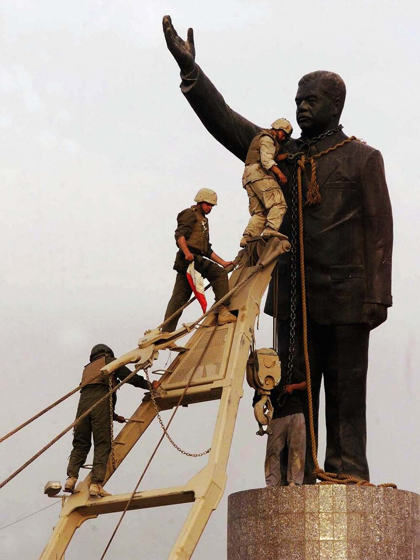 US marines climb to topple the statue of Saddam Hussein in Baghdad