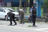 Police check the scene after two bomb blasts in Surat Thani