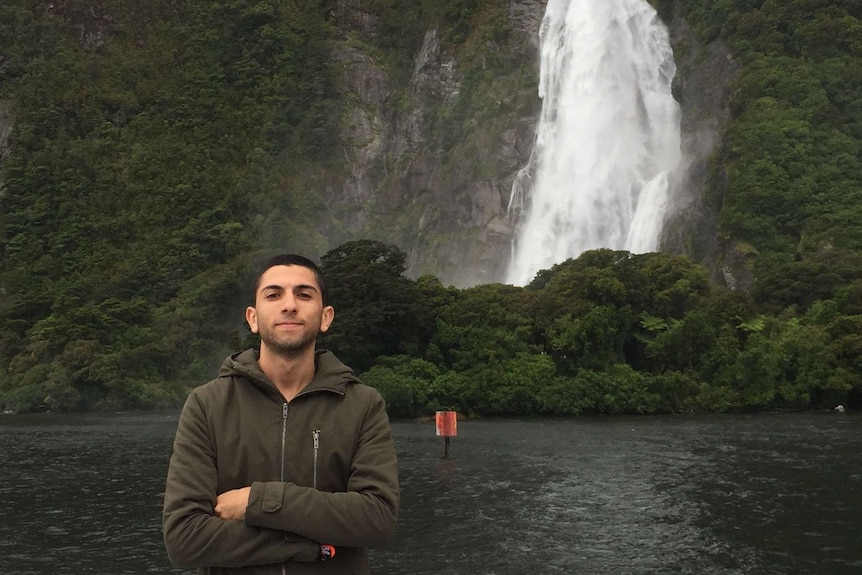 Charbel Elaro standing in front of a waterfall at Milford Sound, New Zealand.