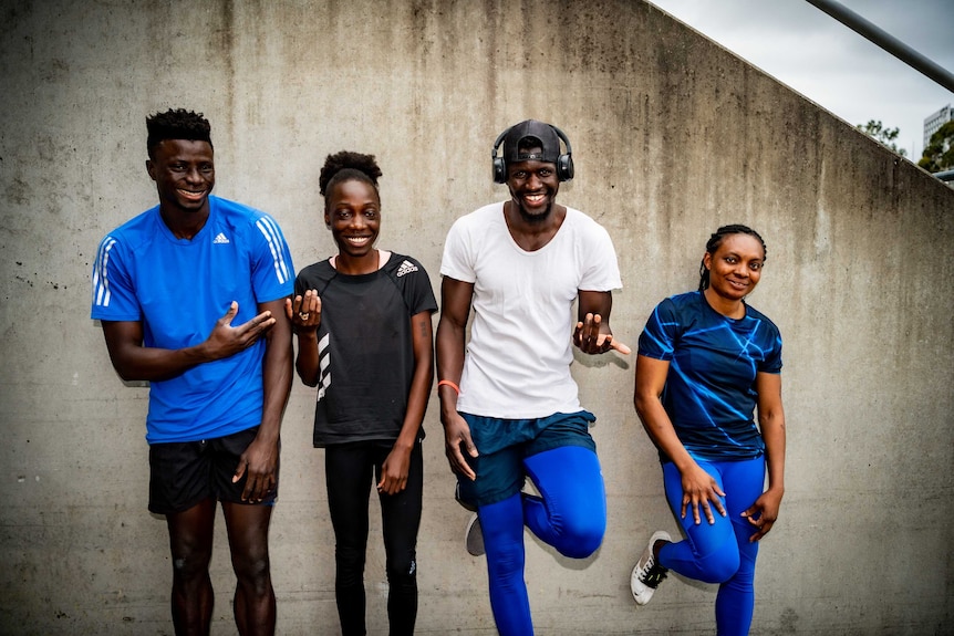 Four athletes pose near a terrace