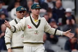 Steve Smith stands with his arms outstretched with David Warner and Tim Paine during a Test match.