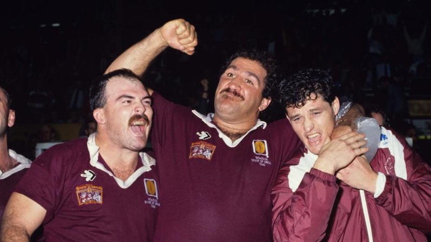 three men in maroon football jerseys celebrating