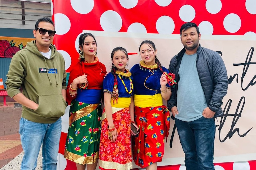 a group shot of 5 people, men on either end and three women in traditional Nepalese attire in the middle