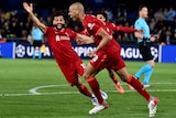 A Liverpool player runs away from goal with his mouth open after scoring, while an overjoyed teammate runs towards him.