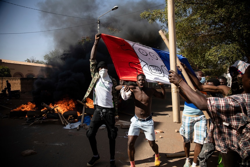 Protesters hold a French flag with a skull and crossbones drawn on it.