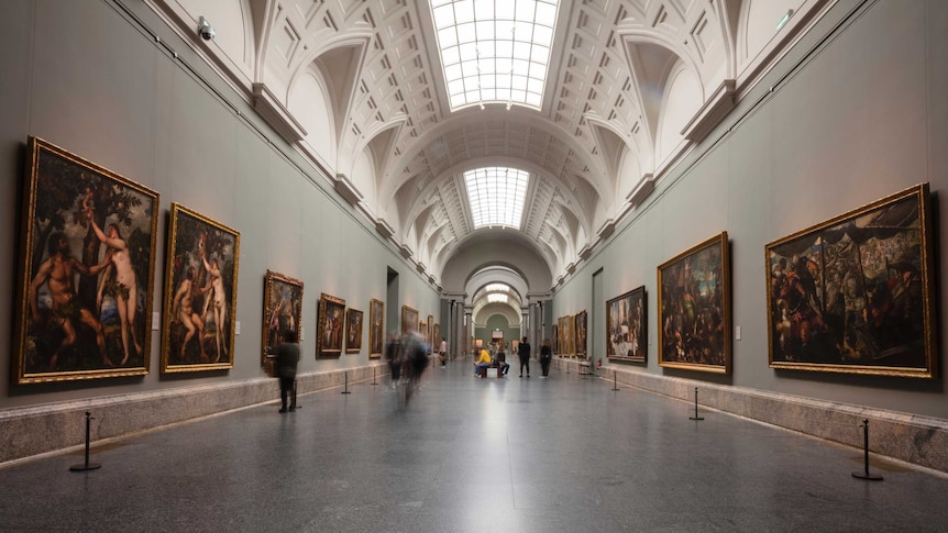 Visitors walk through a long high-ceiled gallery at the El Prado museum in Madrid.