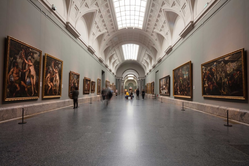 Visitors walk through a long high-ceiled gallery at the El Prado museum in Madrid.