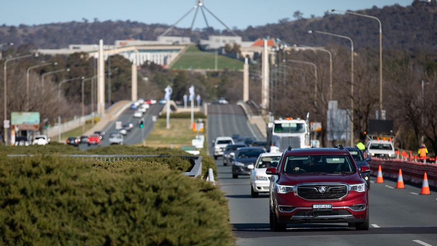 A red car drives down a main Canberra road.