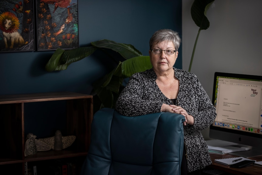 Leanne Groombridge of Advocacy Tasmania stands in an office before a computer monitor.