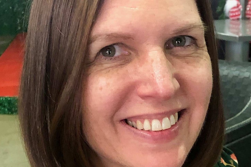 Close up of Lyza Norton with brown hair smiling and looking off to the right of screen