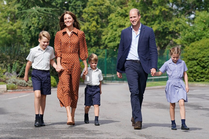 Prince William and his wife Catherine pictured with their children, linking hands, in school uniforms