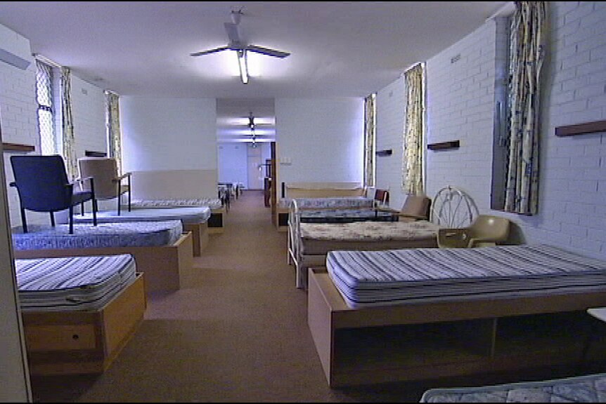 A dingy dormitory with stripped beds in it.