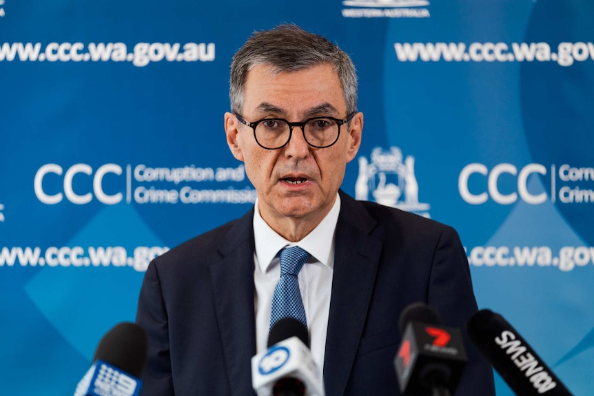 A man in glasses fronts a press pack