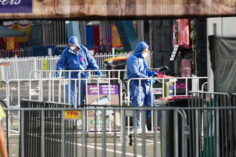 Two people dressed in blue taking pictures at a fairground 