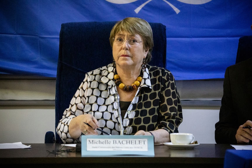 A woman wearing glasses is seated at a desk