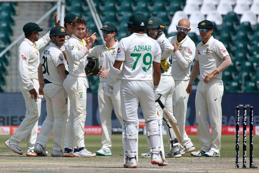 Azhar Ali looks at the Australia team, who motion to him with their fingers pointing up