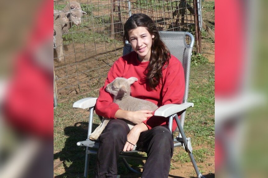 A young girl named Alanah Yukic sits with a goat on her lap.
