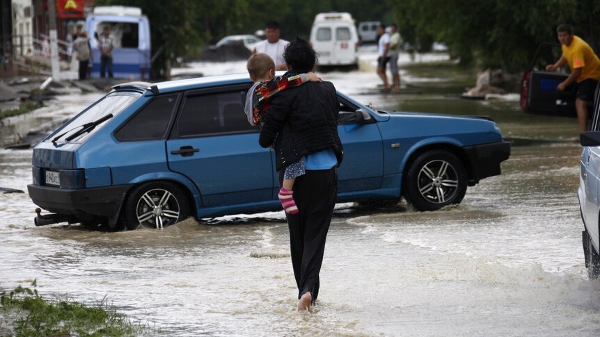 A local resident walks with her child through a flooded street in the southern Russian town of Krymsk.