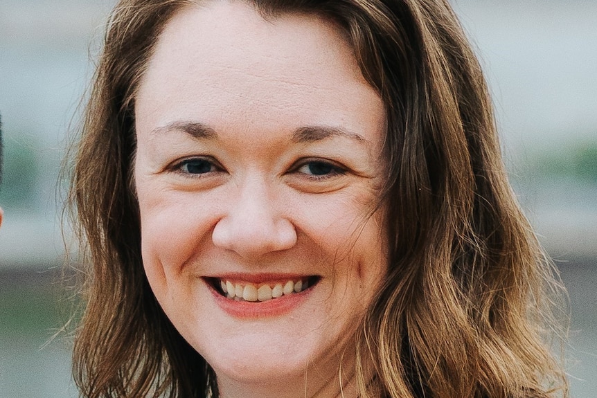 Close up of a middle aged woman with dark hair smiling at the camera 