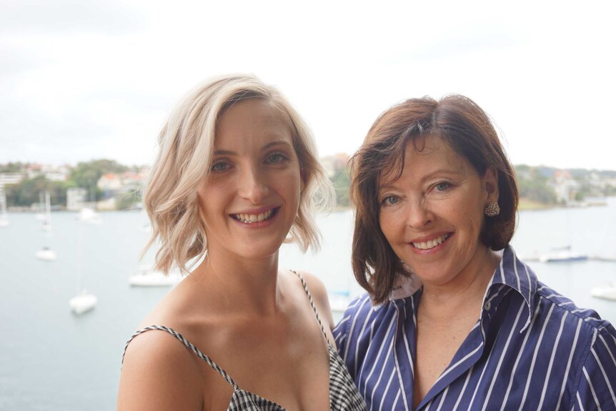 Midshot of Judi Green and her daughter, with boats and Sydney harbour in the background.