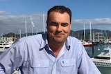 Whitsunday MP Jason Costigan smiling while standing at the marina in Airlie Beach.