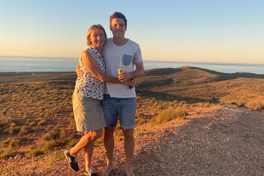 Two people standing in twilight with the ocean in the background