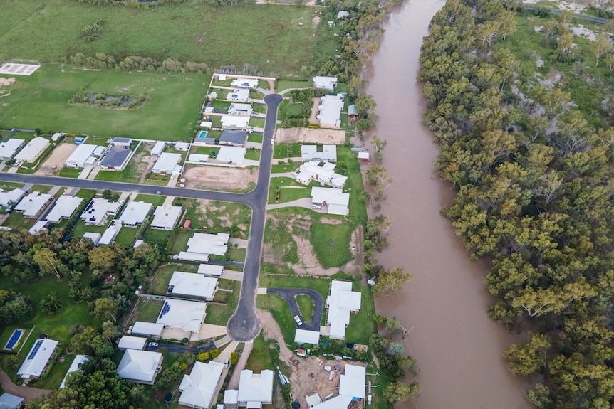 an aerial photo of a river in flood and houses on the side of a levee bank