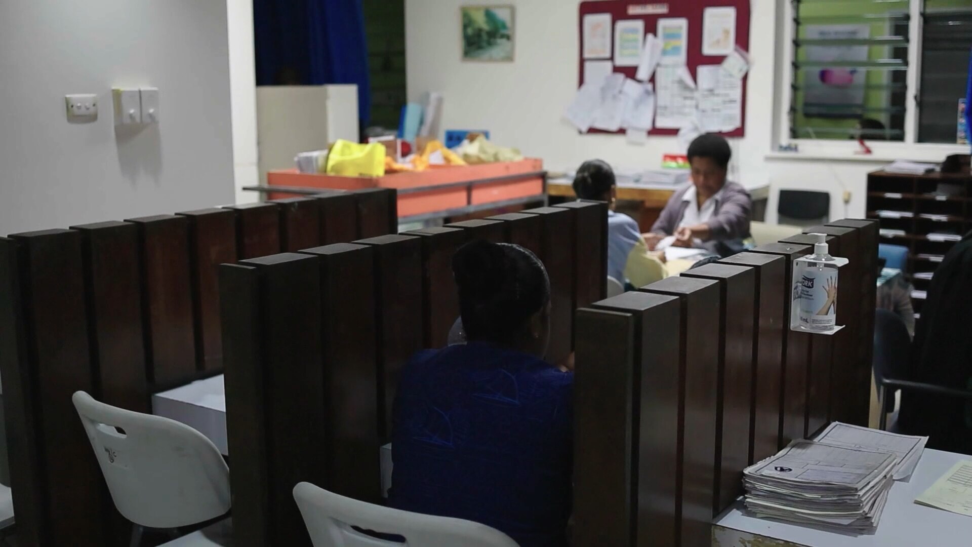 A woman sitting at a counselling booth in a hospital.