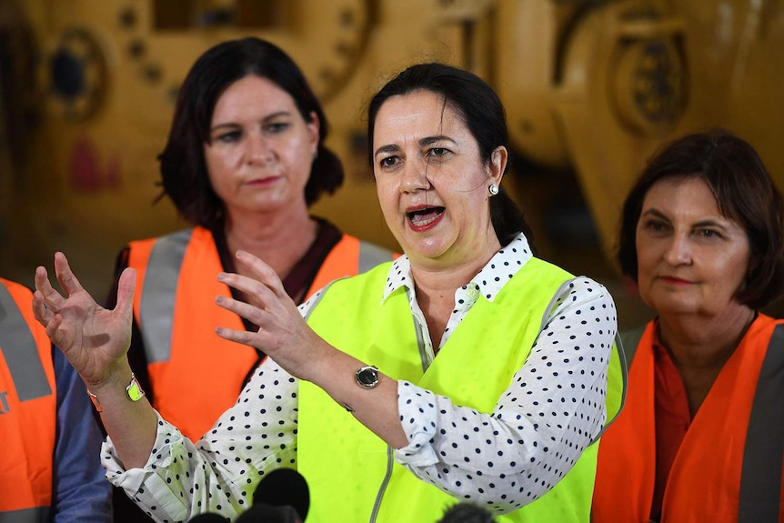 Queensland Premier Annastacia Palaszczuk (centre) speaking with hands raised at press conference in Mackay in north Queensland.