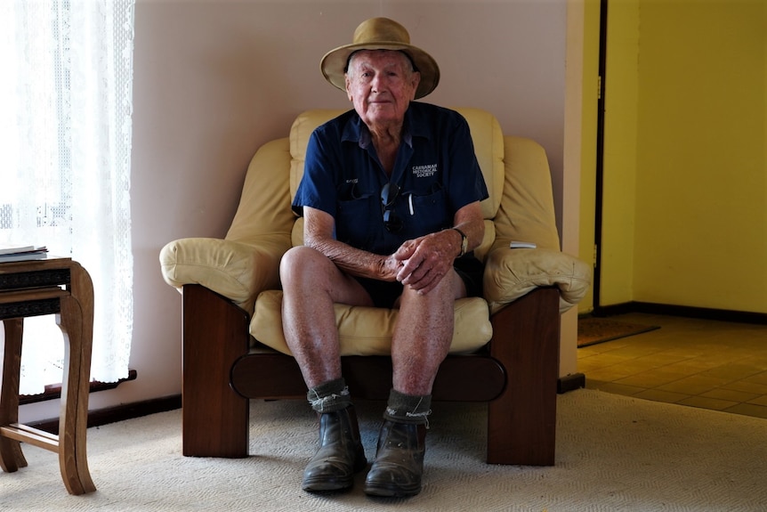 Homme âgé assis dans un fauteuil jaune. 