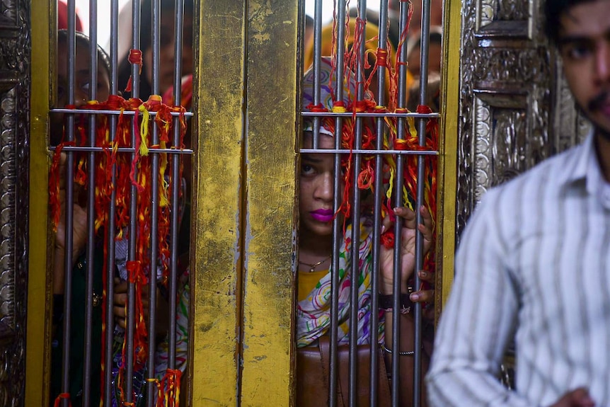 A woman peeks through a golden gate in Kerala