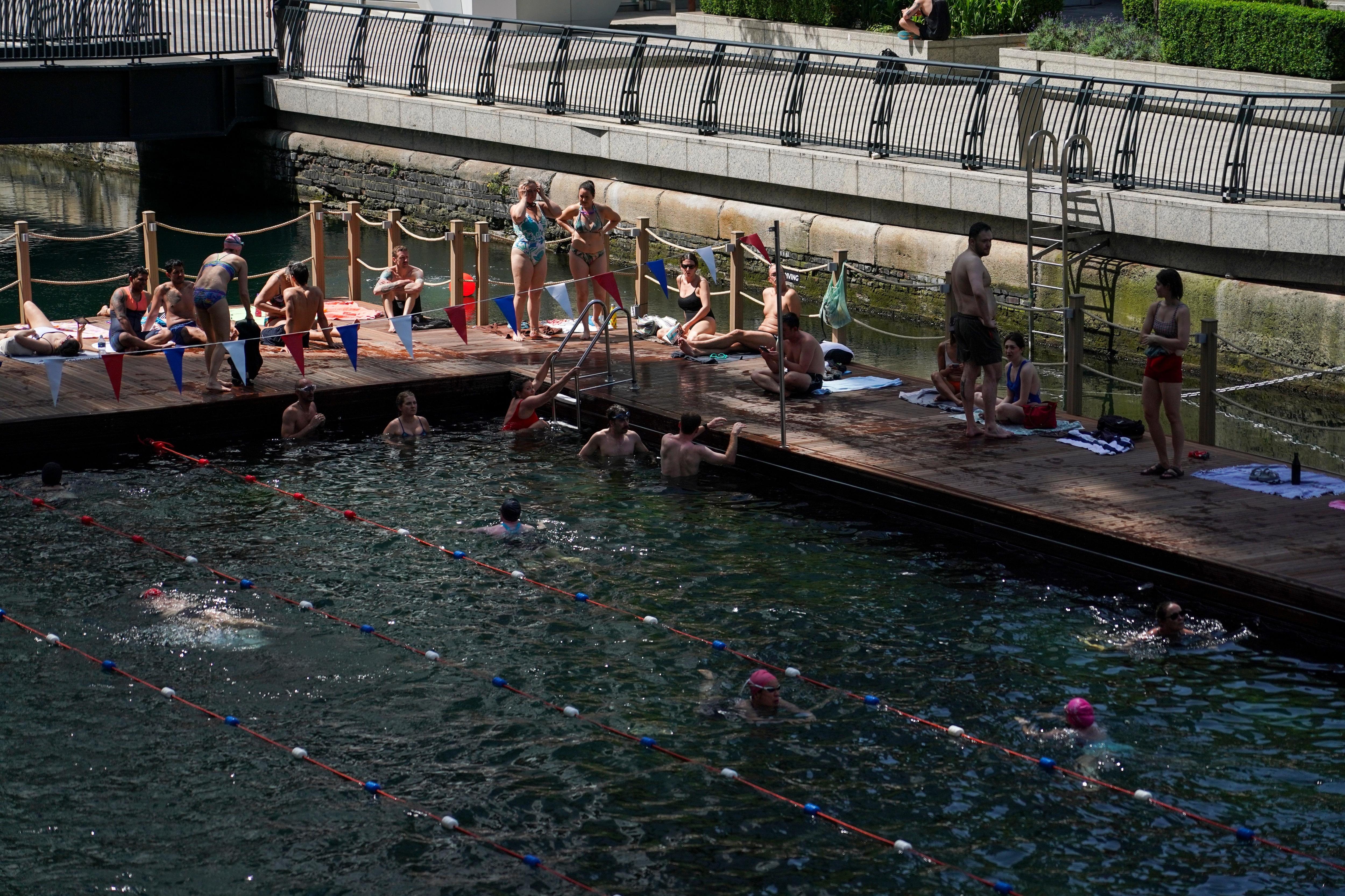 People swim in an outdoor swimming pool in London.