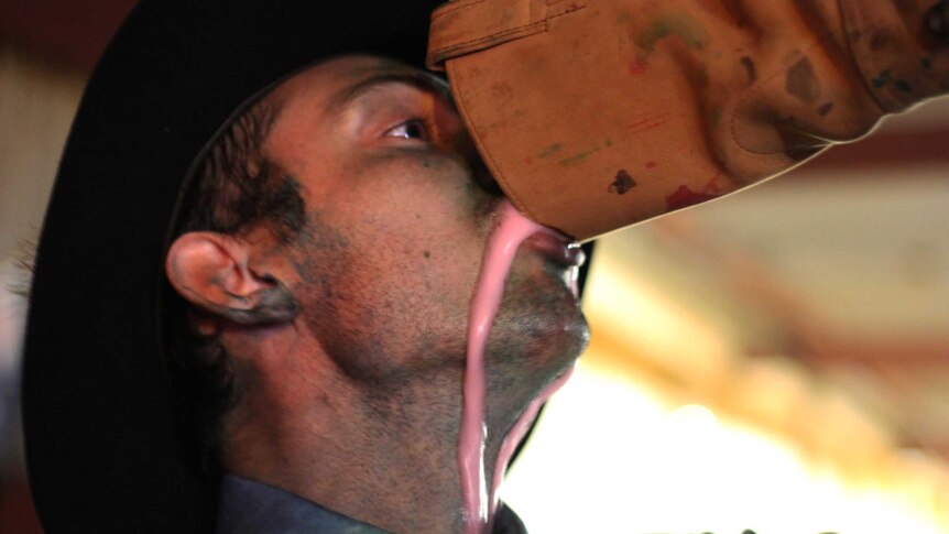 A man drinks from a cowboy boot.