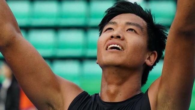 Li Tu holds his arms in the air and looks skyward