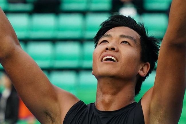 Li Tu holds his arms in the air and looks skyward