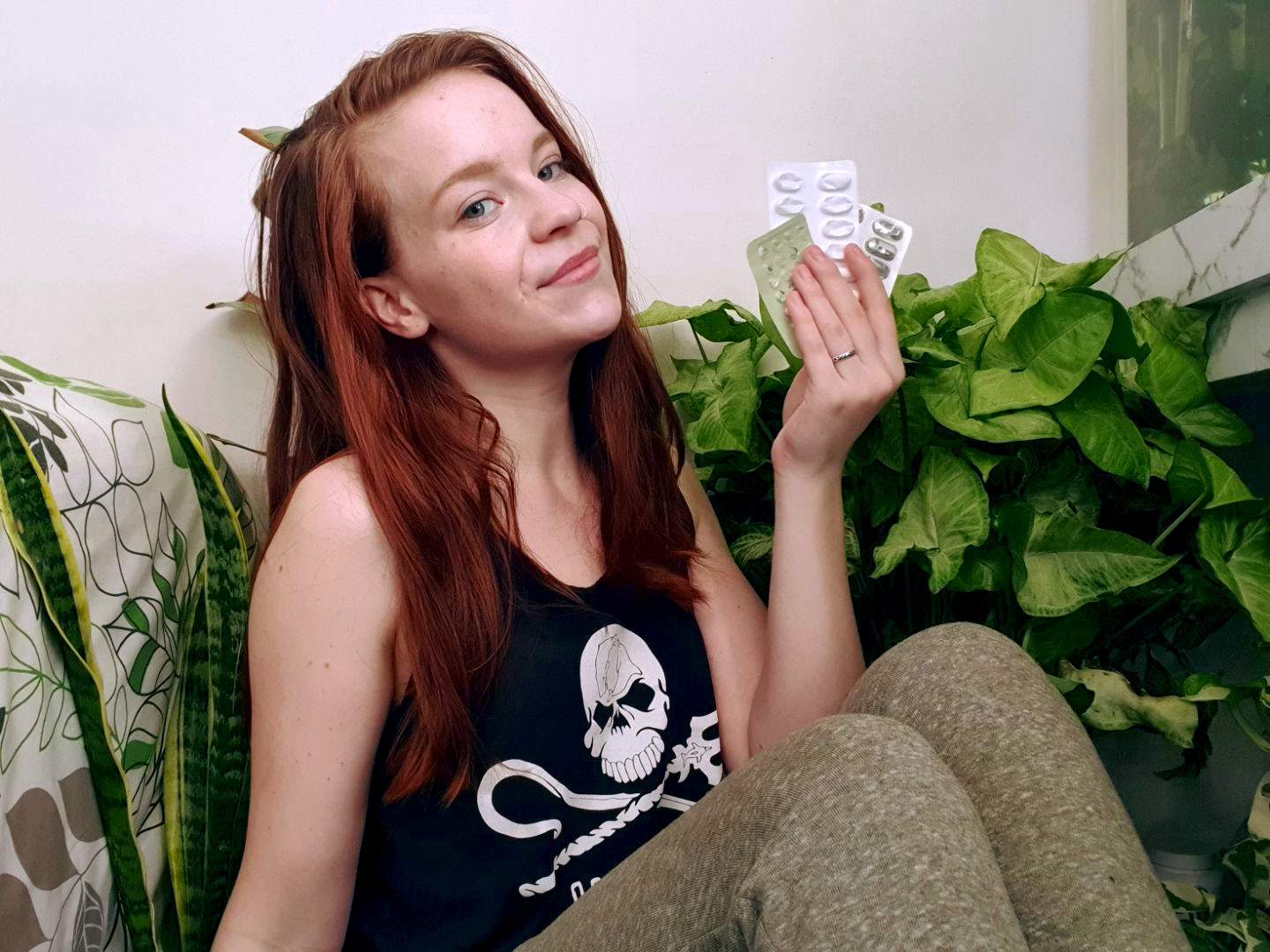 Kaitlyn Gillies sits in front of a house plant holding empty medication packaging, for a story about reducing waste.