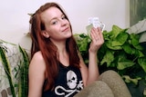 Kaitlyn Gillies sits in front of a house plant holding empty medication packaging, for a story about reducing waste.