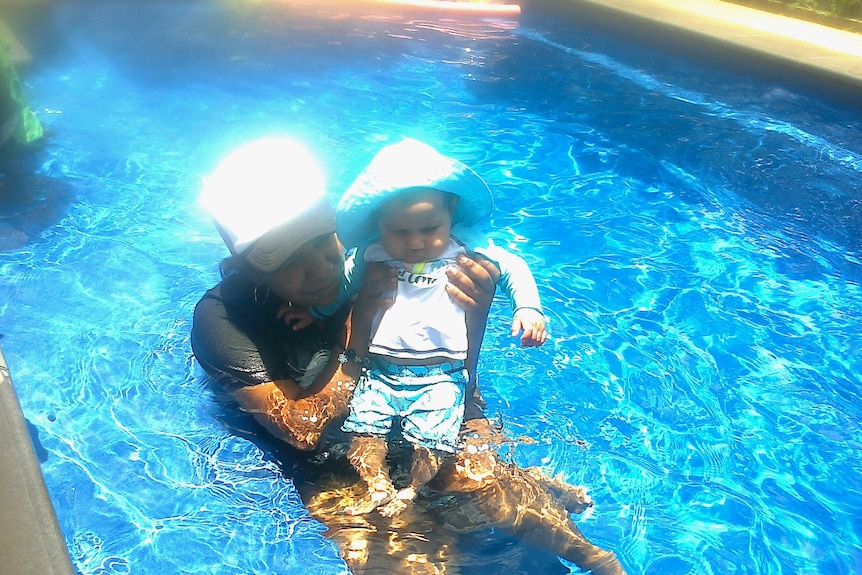 A woman in a pool with a baby
