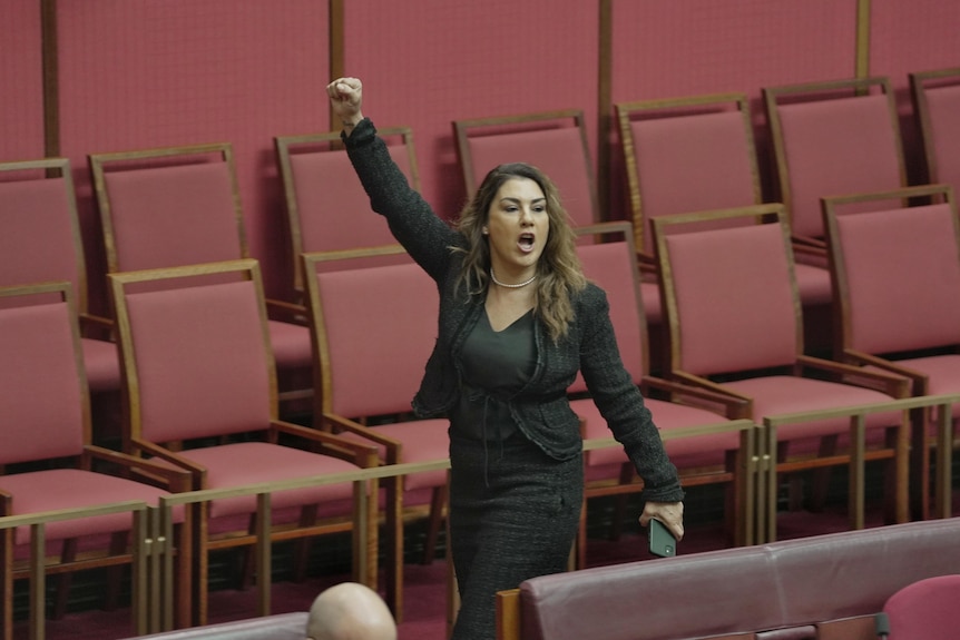 Lidia Thorpe raises a fist in the air as she walks out of Parliament 