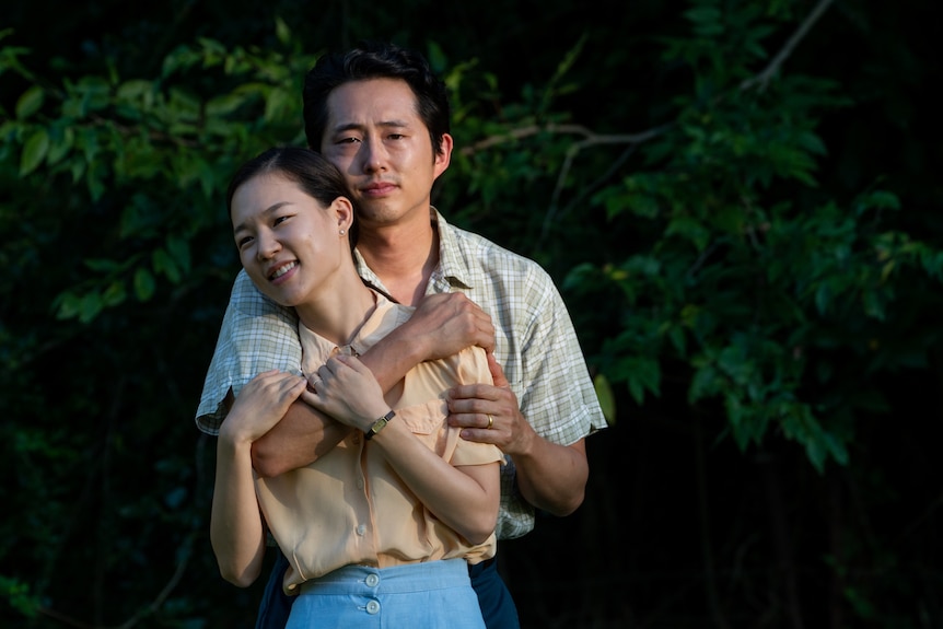 A still from the film Minari with Steven Yeun and Han Ye-ri, a husband and wife hugging