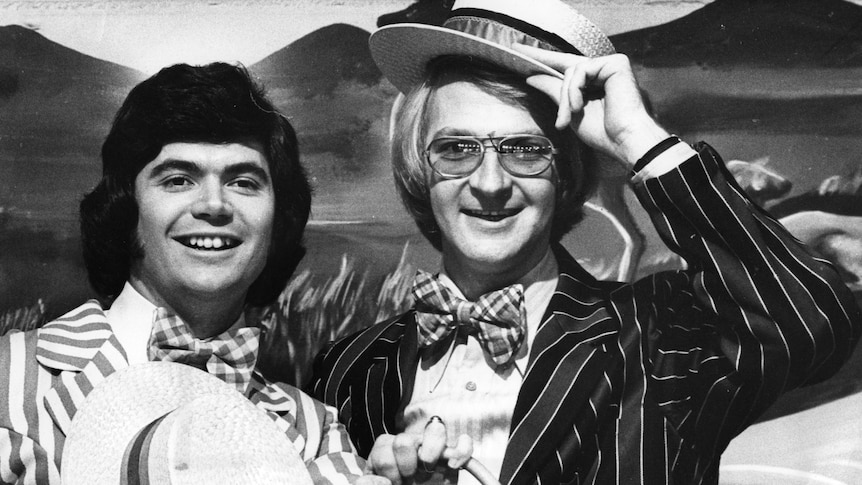 A black and white photo of Daryl Somers and John Blackman dressed up in suits.