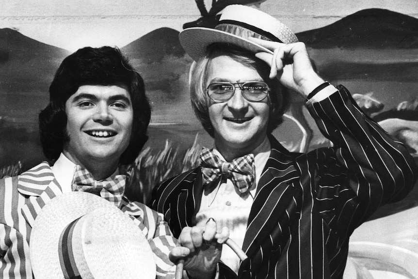 A black and white photo of Daryl Somers and John Blackman dressed up in suits.